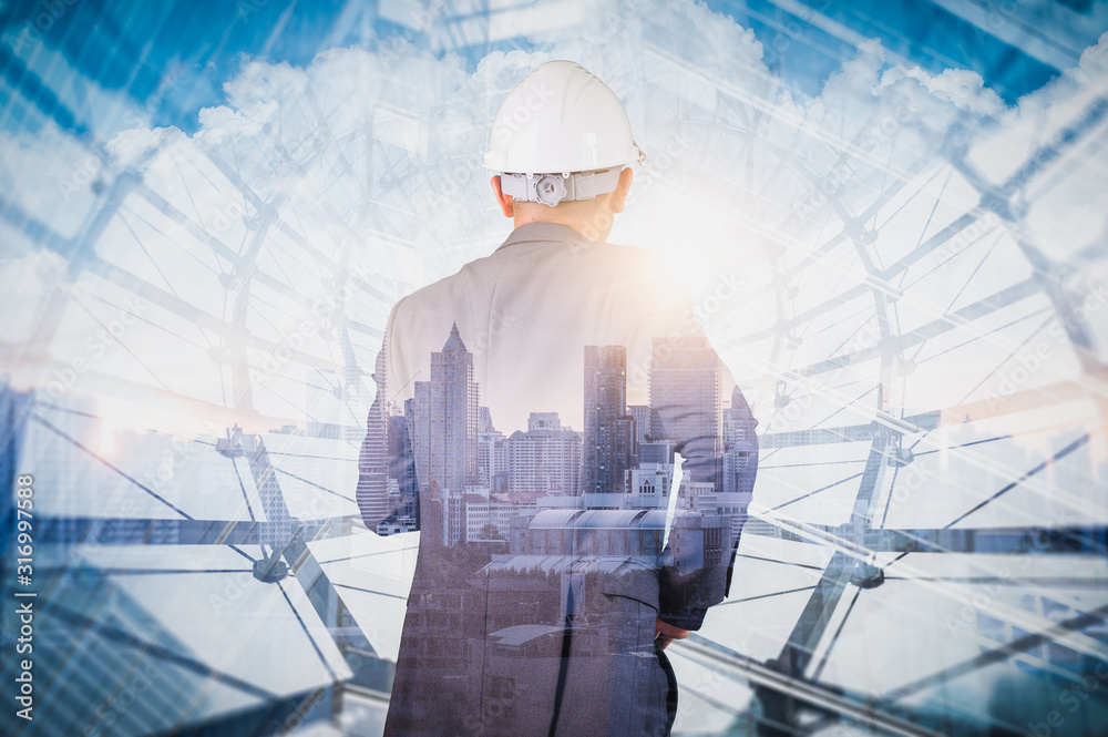 The double exposure image of the engineer standing back during sunrise overlay with cityscape image. The concept of engineering, construction, city life and future. The double exposure image of the engineer standing back during sunrise overlay with cityscape image. The concept of engineering, construction, city life and future.