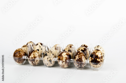 18 quail eggs in plastic packaging on white background