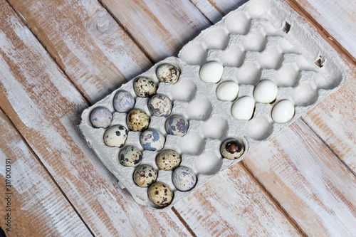 Fresh and boiled quail eggs on craft cell on wooden background