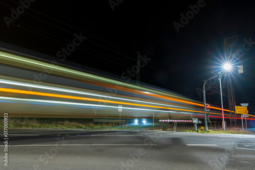 Doppeldecker Reisezug befährt einen Überweg bei Nacht