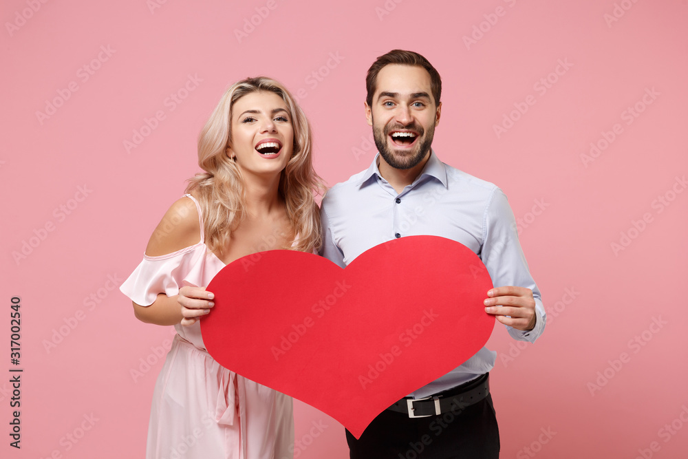 Laughing young couple two guy girl in party outfit celebrating posing isolated on pink background. People lifestyle Valentine's Day, Women's Day birthday holiday concept. Hold empty blank red heart. Laughing young couple two guy girl in party outfit celebrating posing isolated on pink background. People lifestyle Valentine's Day, Women's Day birthday holiday concept. Hold empty blank red heart.