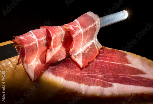 Dry Spanish ham, Jamon Serrano, Italian prosciutto crudo or Parma ham, whole leg isolated on black background photo