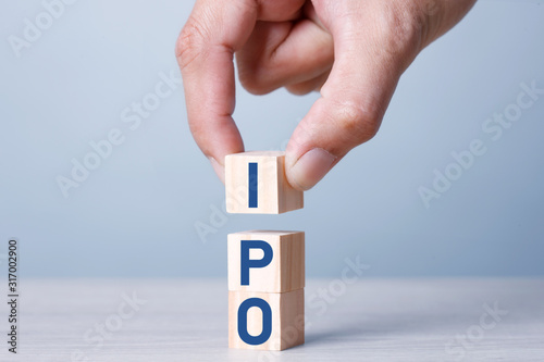Busiiness Concept IPO Stack of wooden blocks with letters, Initial Public Offering IPO concept, random letters around, Blue tone background photo