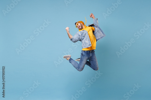 Cheerful young hipster guy in fashion jeans denim clothes posing isolated on pastel blue background studio portrait. People emotion lifestyle concept. Mock up copy space. Jumping doing winner gesture.