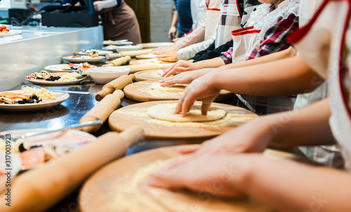 Children cook pizza. Master class from the chef in a restaurant, Close-up of children's hands roll out the dough photo