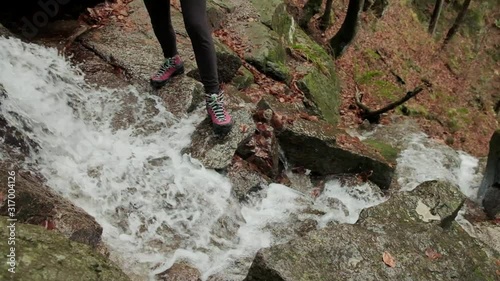 Lady walking through a waterfall in Slow motion as the water falls underneth her. Hiking waterproof boots. Waterfall of Veliki Sumik in the eastern part of Slovenia. photo