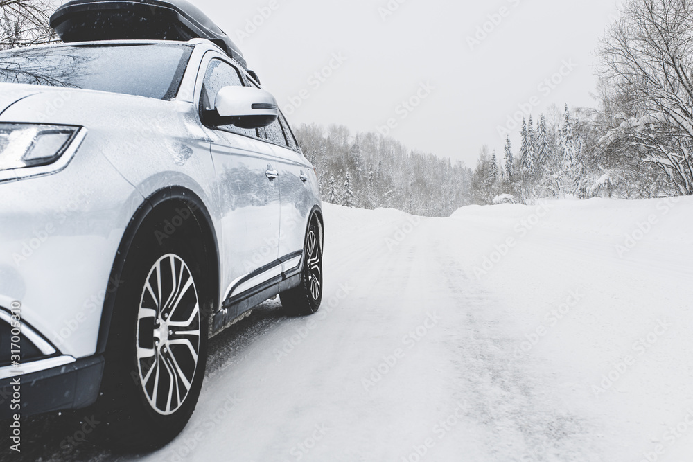 Suv car with rooftop cargo carrier trunk stay on roadside of winter mountain road in snowy blizzard. Family trip to ski resort. Winter holidays adventure. car on winter road