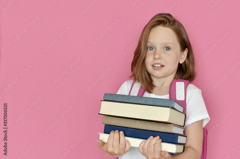 School girl with emotional look holding in hands heavy books, education, reading, back to school concept, studio portrait, pink background. School girl with emotional look holding in hands heavy books, education, reading, back to school concept, studio portrait, pink background.