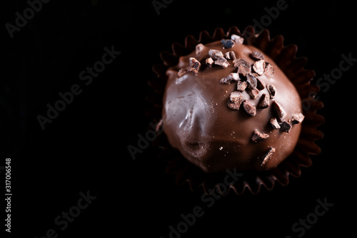 One Single Handmade Chocolate Praline Close Up View. Dark Background with Copy Space
