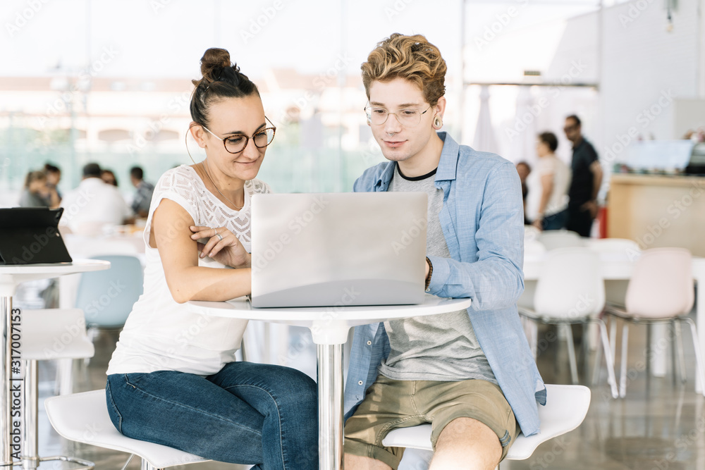Young man and a girl working together with a laptop in a coworking Young man and a girl working together with a laptop in a coworking