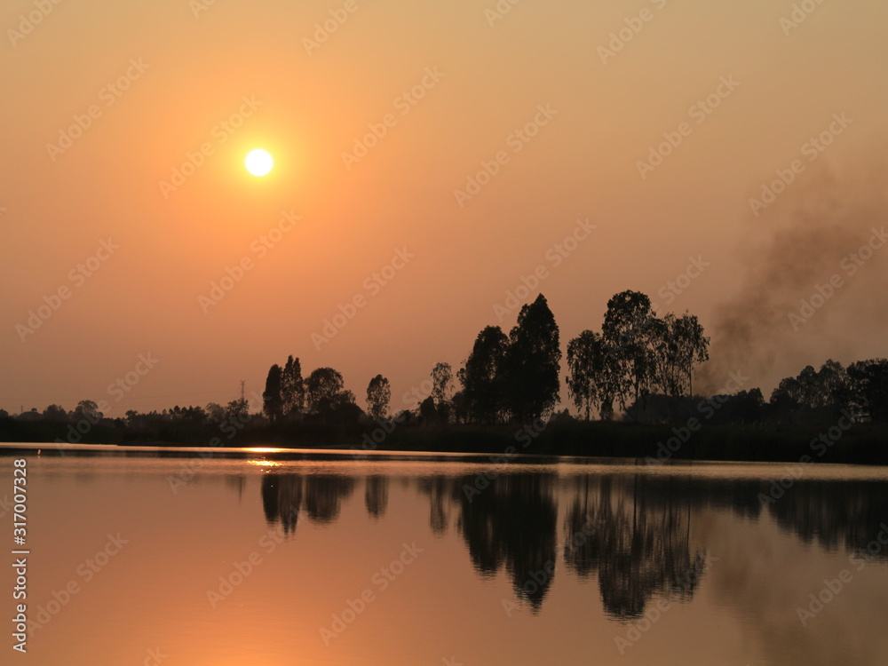  silhouette tree in asia with sunset.Tree silhouetted against a setting sun.Dark tree on open field dramatic sunrise and reflection in water.