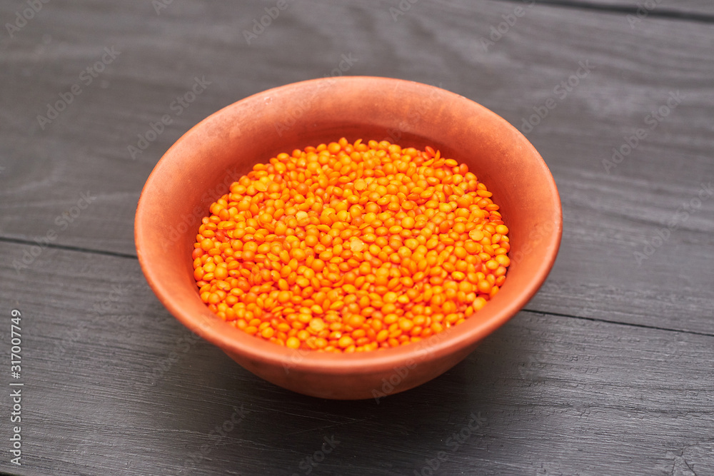 lentil grains in a plate on a black wooden background. lentil grains in a plate on a black wooden background.