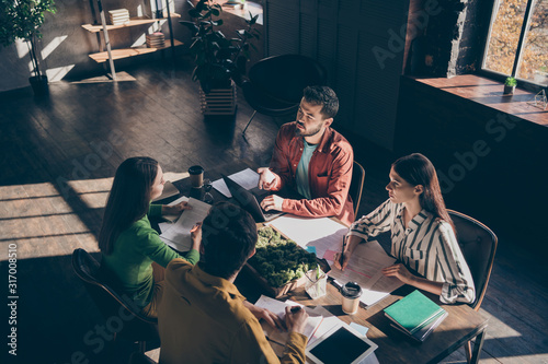 Four busy experienced businesspeople wearing casual formal-wear discussing delegation company growth income at modern industrial loft wooden interior workplace workstation photo