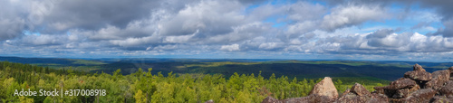 Panorama of a forest valley with blue sky and clouds. The view from the mountain. Travel and vacation in the mountains.
