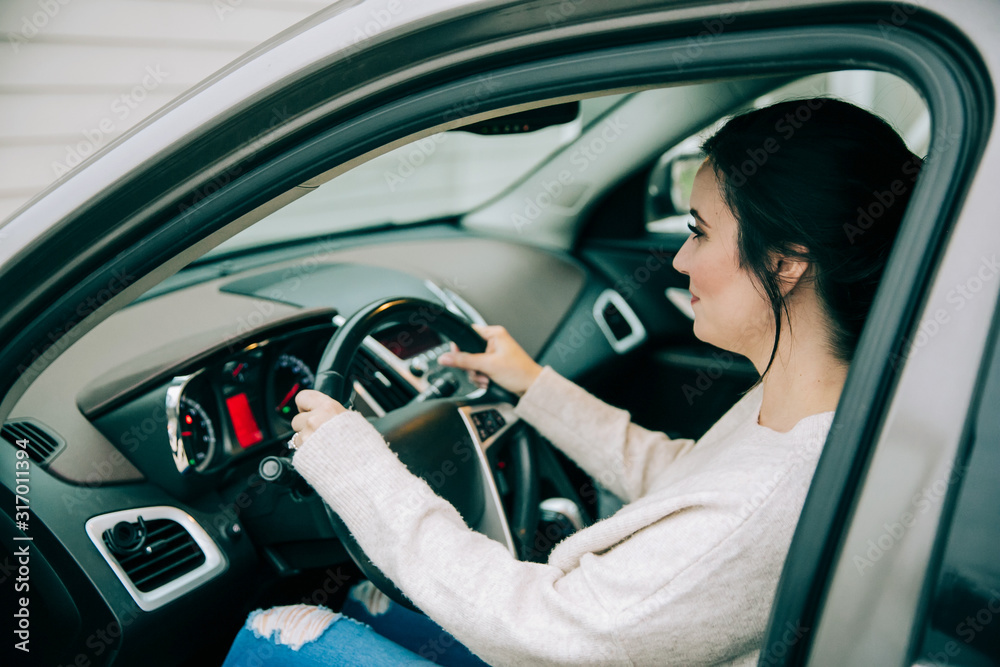 brunette woman in the driver's seat of a tan gold neural sedan car brunette woman in the driver's seat of a tan gold neural sedan car