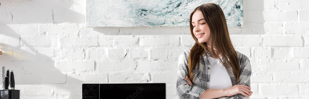 panoramic shot of smiling and attractive woman standing near microwave in kitchen - obrazy, fototapety, plakaty 