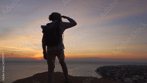 handsome middle eastern male standing on a cliff and looking ahead