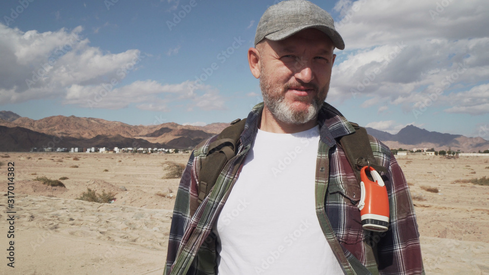 Naklejka premium portrait of handsome senior male standing on a road at desert