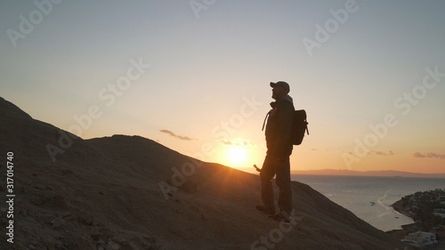 Handsome senior traveler with selfie stick climb up a hill at sunrise © Alexander Belinskiy