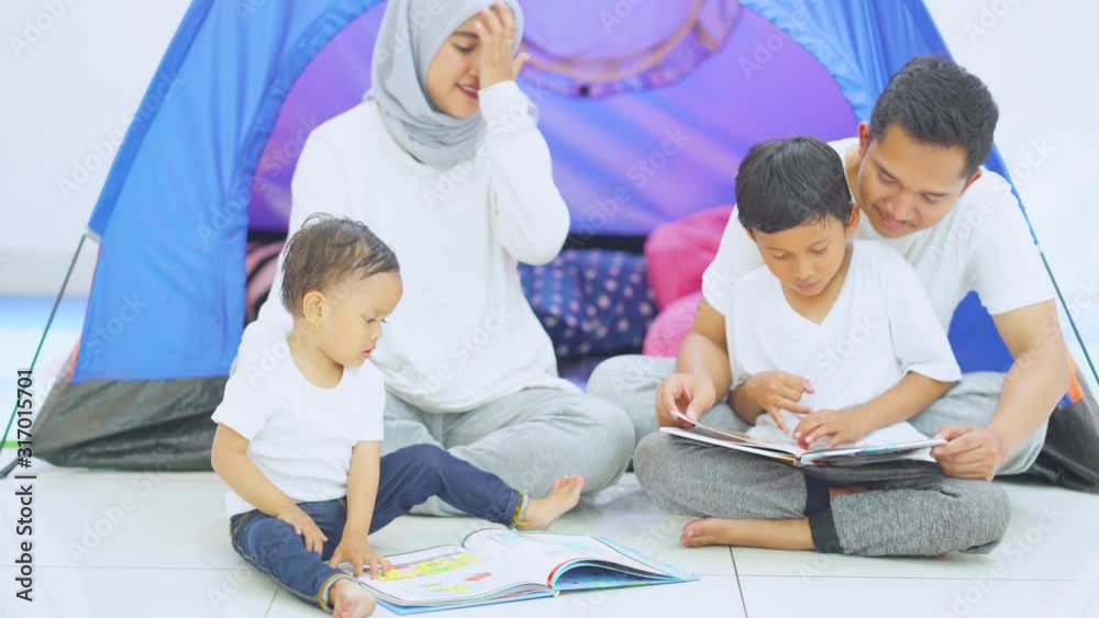 Muslim family reading story book together with camping tent background at home. Shot in 4k resolution
