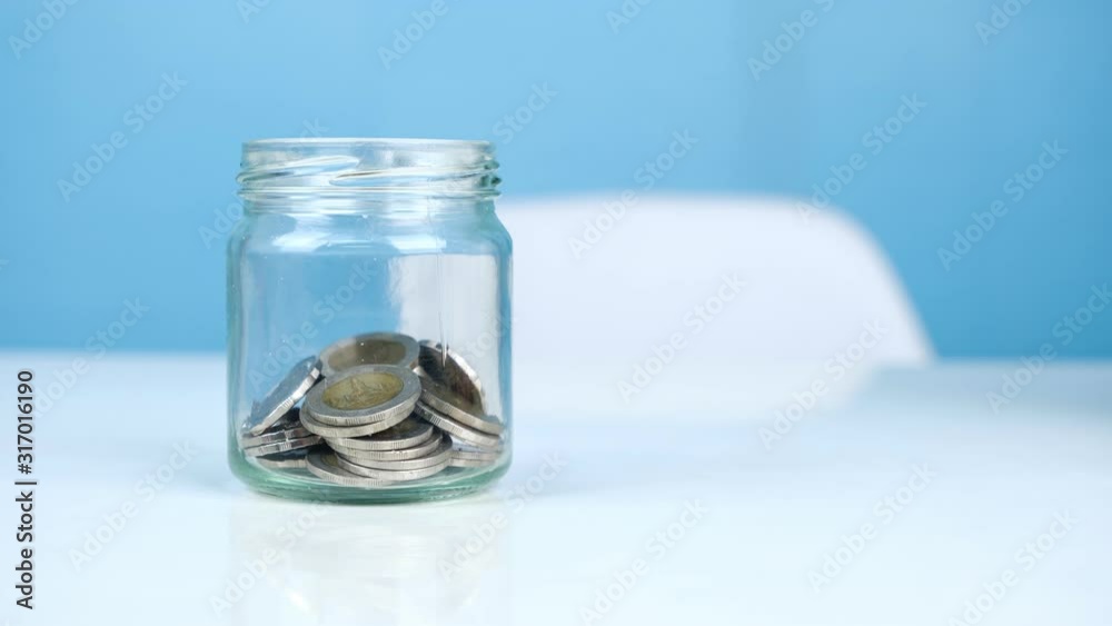 Coin money into glass jar, Saving money concept, 4K stop motion.
