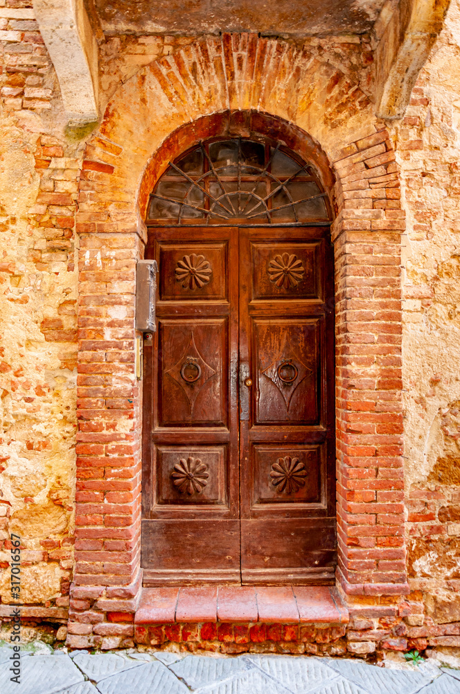 Pienza in Tuscany, Italy. View of an architectural detail with ancient wooden door. UNESCO heritage village, famous for the 