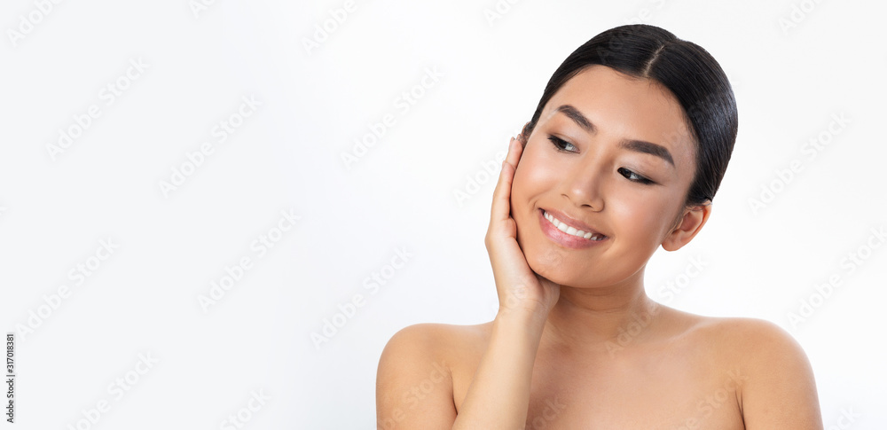 Soft touch. Smiling asian girl touching her velvet skin on cheek Soft touch. Smiling asian girl touching her velvet skin on cheek