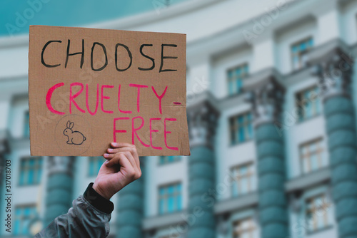 The phrase " Choose cruelty free " on a banner in men's hand. Animal rights protest. Protection. City. Urban. Rally. Freedom. Stop animal testing. Equality. Justice. Care. Life. Humanity