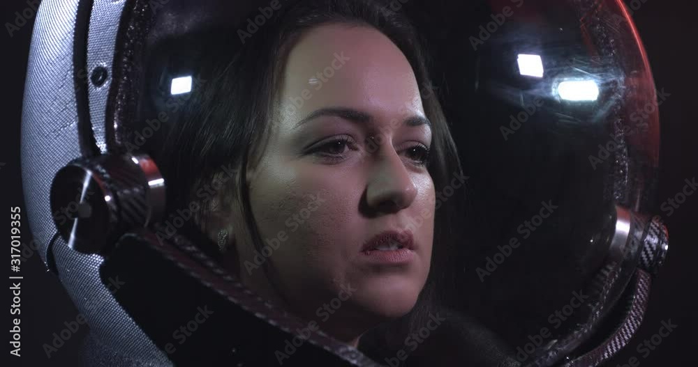 Young Beautiful Female Astronaut In Space Helmet Looking At Camera. She Is Exploring Outer Space In A Space Suit. Science And Technology Related 4K Concept Footage.