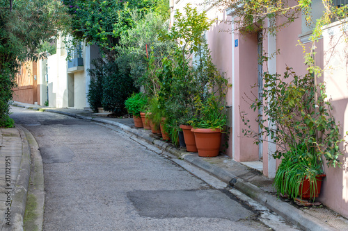 Fototapeta Naklejka Na Ścianę i Meble -  Narrow alley in Plaka Athens old town district. Sidewalk with plants and trees.