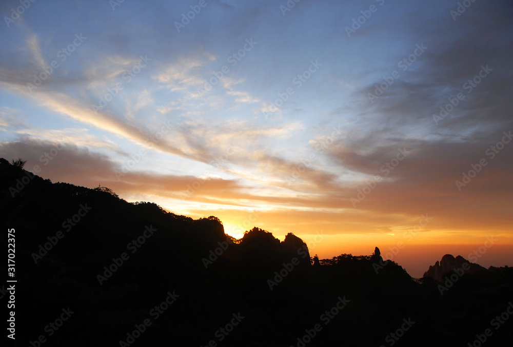 Huangshan Mountain in Anhui Province, China. After sunset on Huangshan with colorful sky and clouds and a silhouette of the mountain. Sunset near the summit of Huangshan Mountain, China.