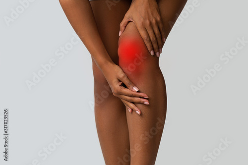 Cropped of black girl touching her injured knee