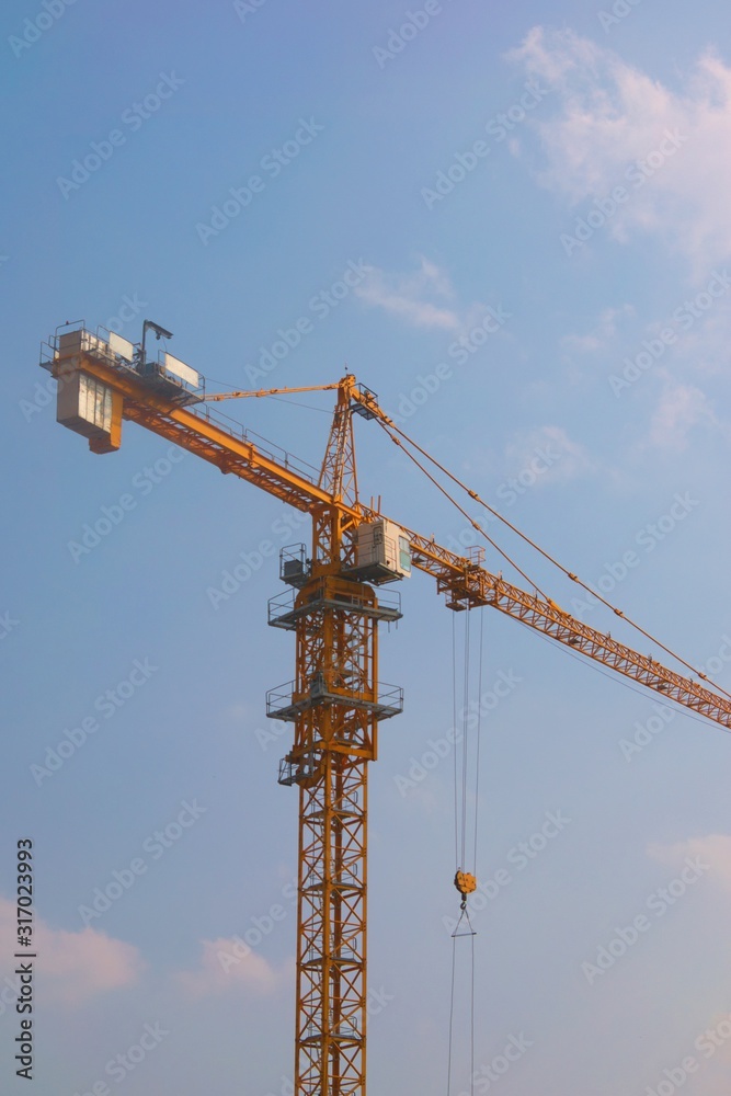 Yellow construction tower crane against a clear blue sky. Low angle shot. Yellow construction tower crane against a clear blue sky. Low angle shot.