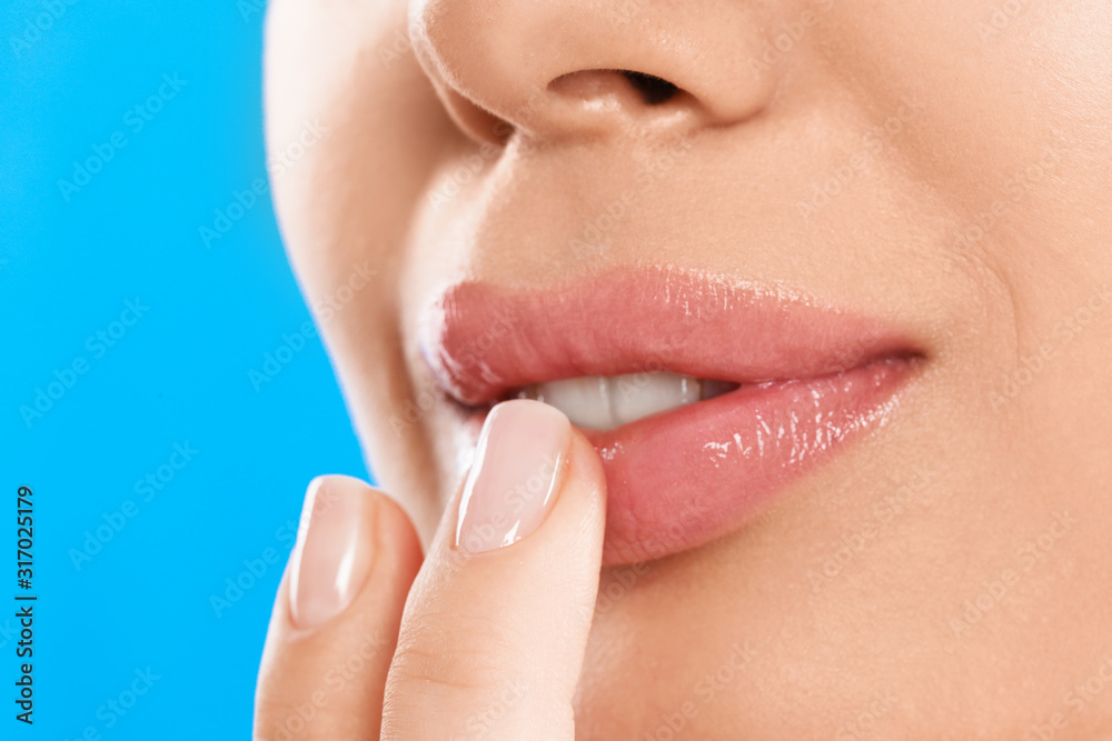 Young woman with beautiful full lips on light blue background, closeup Young woman with beautiful full lips on light blue background, closeup