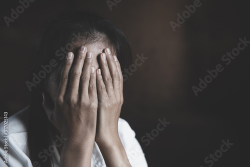 Young girl sitting in dark room feeling pain with life problem. Crying female holding painful hand, The concept of stopping violence against women and rape. International Women's Day