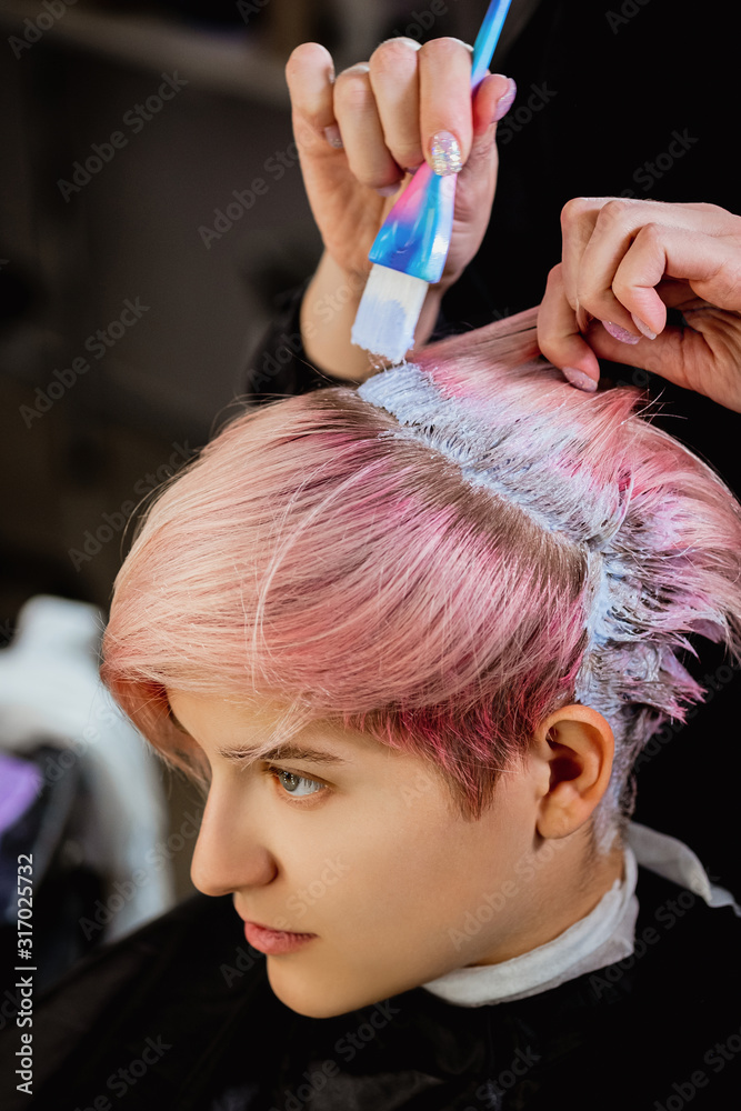 Naklejka premium Hairdresser colorist dyes the hair of a woman to a client in different colors.