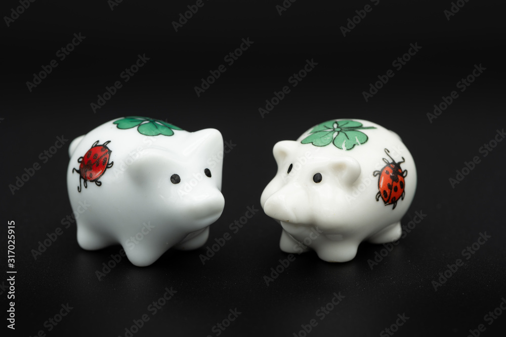 Two small white porcelain piggies, black background Two small white porcelain piggies, black background