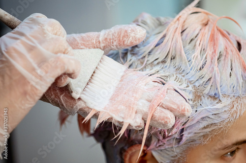 Hairdresser colorist dyes the hair of a woman to a client in different colors.