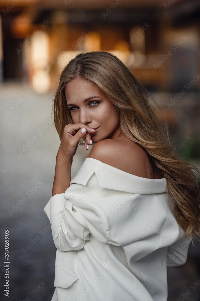 Outdoor full body fashion portrait of fashionable woman in white suit posing in street of east city Outdoor full body fashion portrait of fashionable woman in white suit posing in street of east city