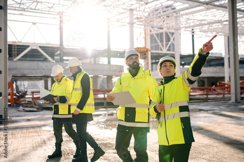 Group of engineers standing outdoors on construction site, working. photo