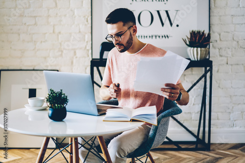 Serious caucasian male writer searching interesting content information for creating new chapter for next bestseller about distance job connected to free home interior on modern laptop computer