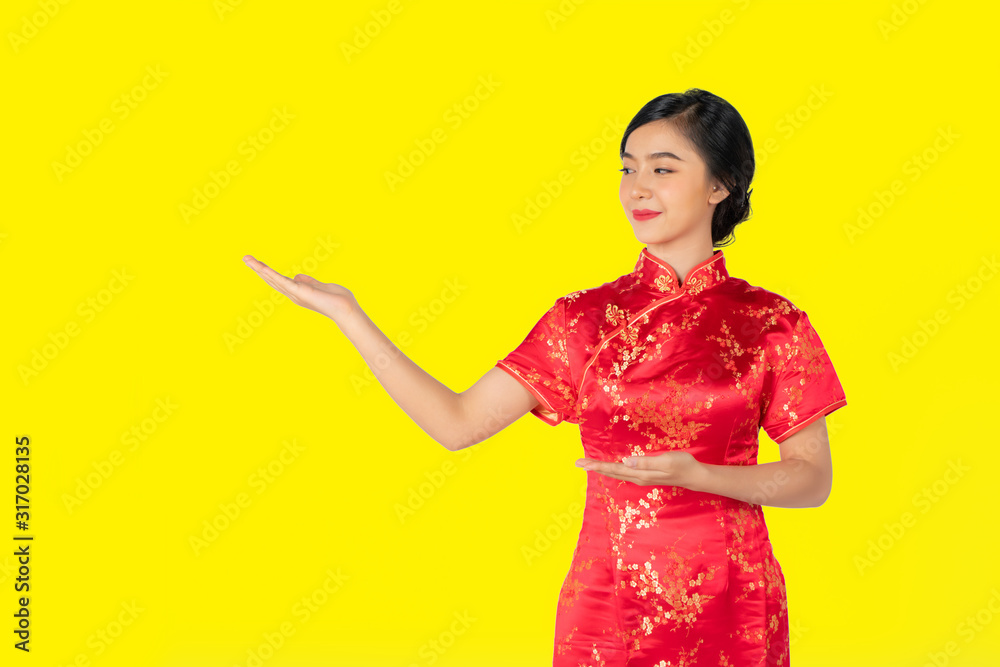 Pretty Asian female with Chinese traditional dress cheongsam or qipao hand showing blank space. Chinese new year concept, female model isolated on yellow background. Pretty Asian female with Chinese traditional dress cheongsam or qipao hand showing blank space. Chinese new year concept, female model isolated on yellow background.