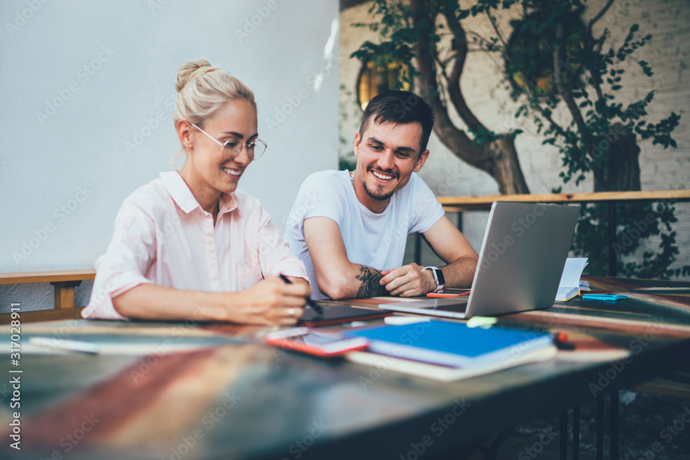 Modern happy young man and woman laughing while doing teamwork Modern happy young man and woman laughing while doing teamwork