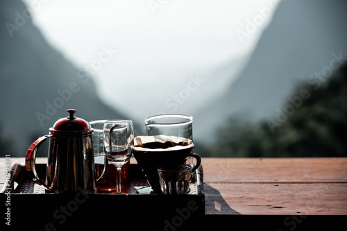 Image of Coffee drip set on wooden table with beautiful landscape mountain heart shape at Coffee Pha Hee, Chiang rai Thailand photo