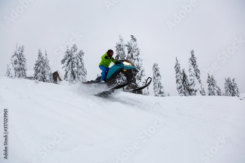 Adventurous Man Riding a Snowmobile in white snow. Taken near Squamish and Whistler, British Columbia, Canada.