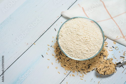 gluten-free brown rice flour. dietary food. vegetarianism. flour in a round plate on a background of scattered rice on a light background photo