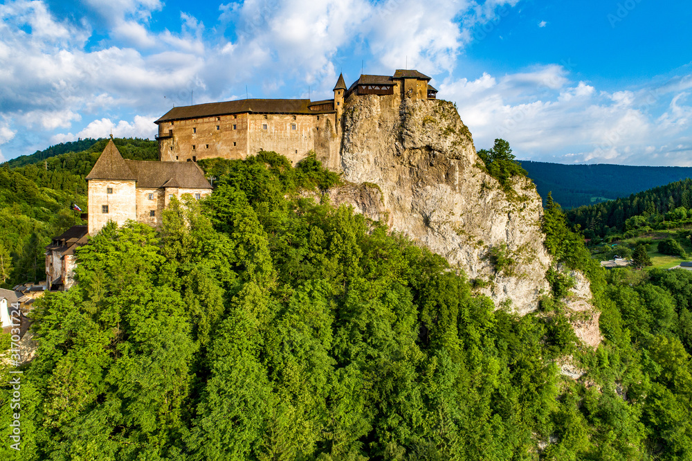Orava castle - Oravsky Hrad in Oravsky Podzamok in Slovakia. Medieval fortress on extremely high and steep cliff by the Orava river. Aerial view in sunrise light in summer