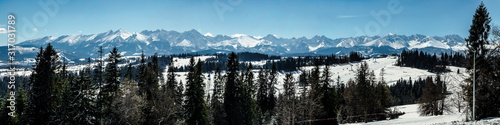 Wide panorama of Tatra mountains in winter, viewed from Bania mountain in Bialka ski resort with ski chair lift. Far view of Kasprowy Wierch, main Tatra ski slope in Poland in the very middle