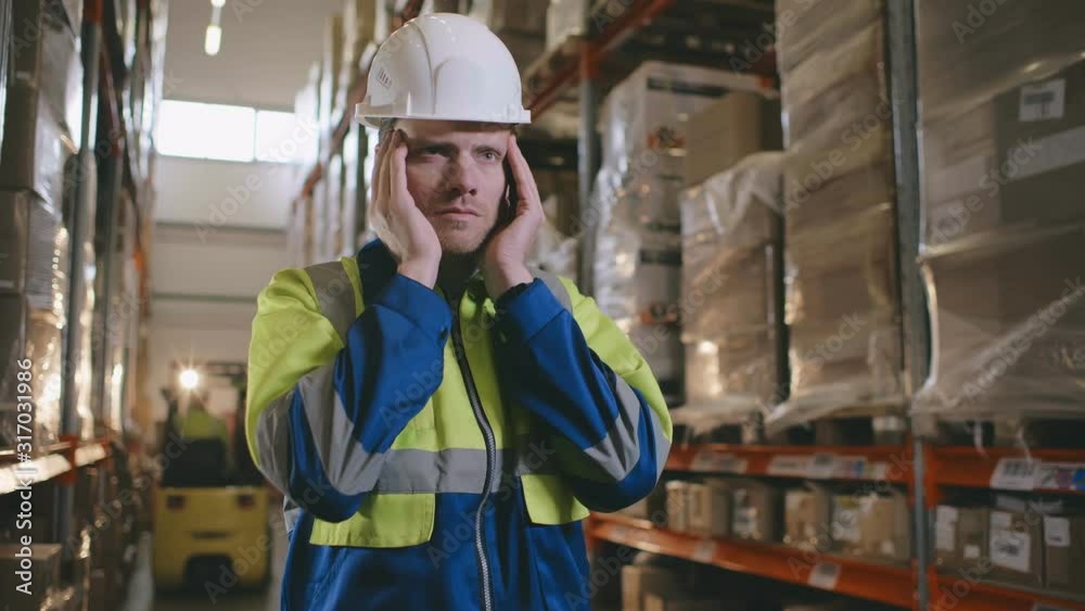 Male warehouse worker suffers from sudden throbbing headache Male warehouse worker suffers from sudden throbbing headache
