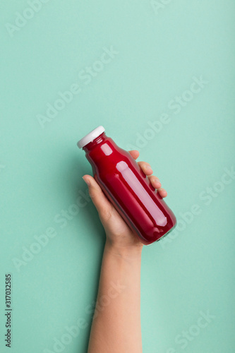 Woman advertising beet detox cocktail in glass bottle photo